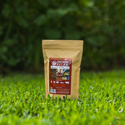 Bag of Smokin' Pecan pecan shell pellets on grass with a blurred green background