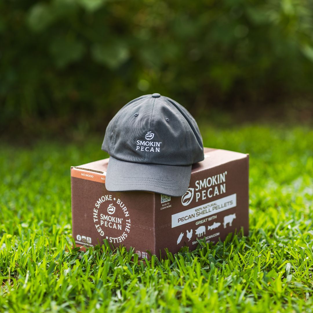 Gray cap on a box of Smokin' Pecan pecan shell pellets in a grassy outdoor setting